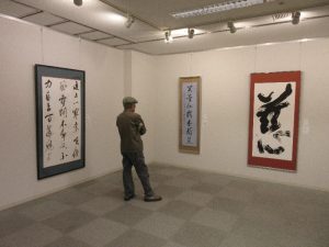 壁に展示されている書を鑑賞する人