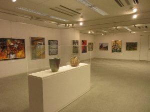 様々な絵画が壁に並ぶ展示室の様子